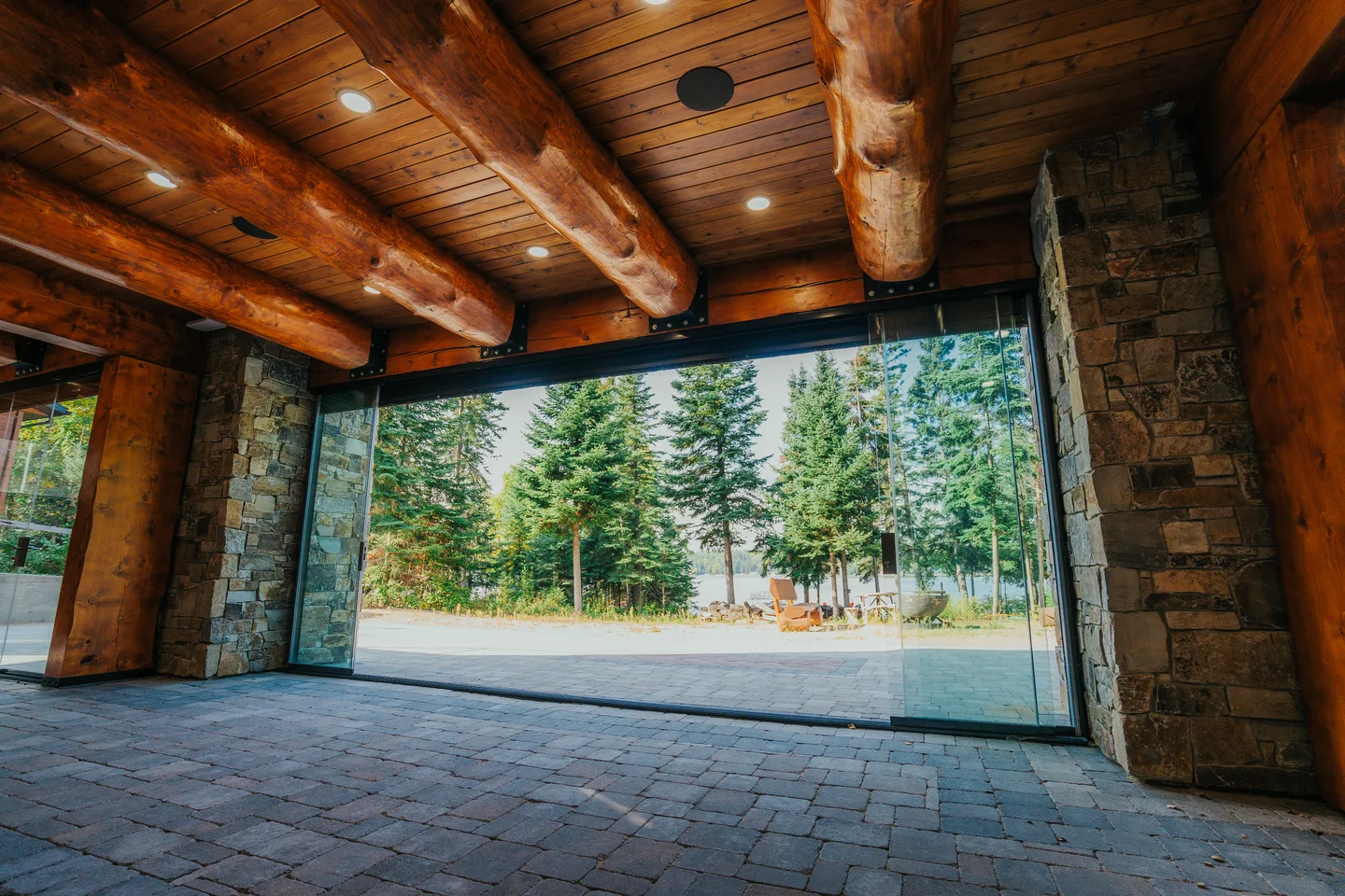 Glass enclosure with panels folded fully open onto a lakeside patio