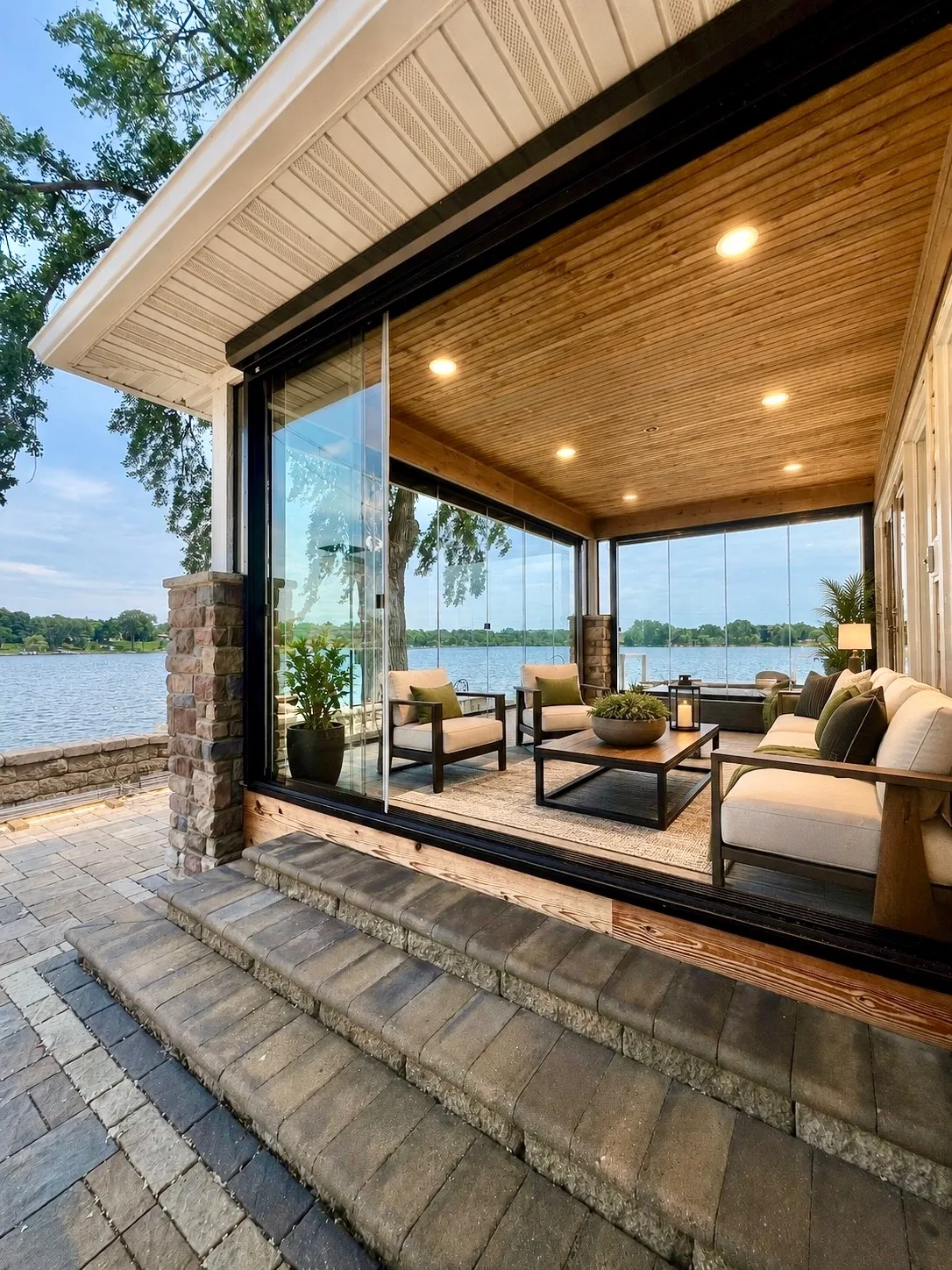 Glazed porch with a wood ceiling opening onto stone steps and the water