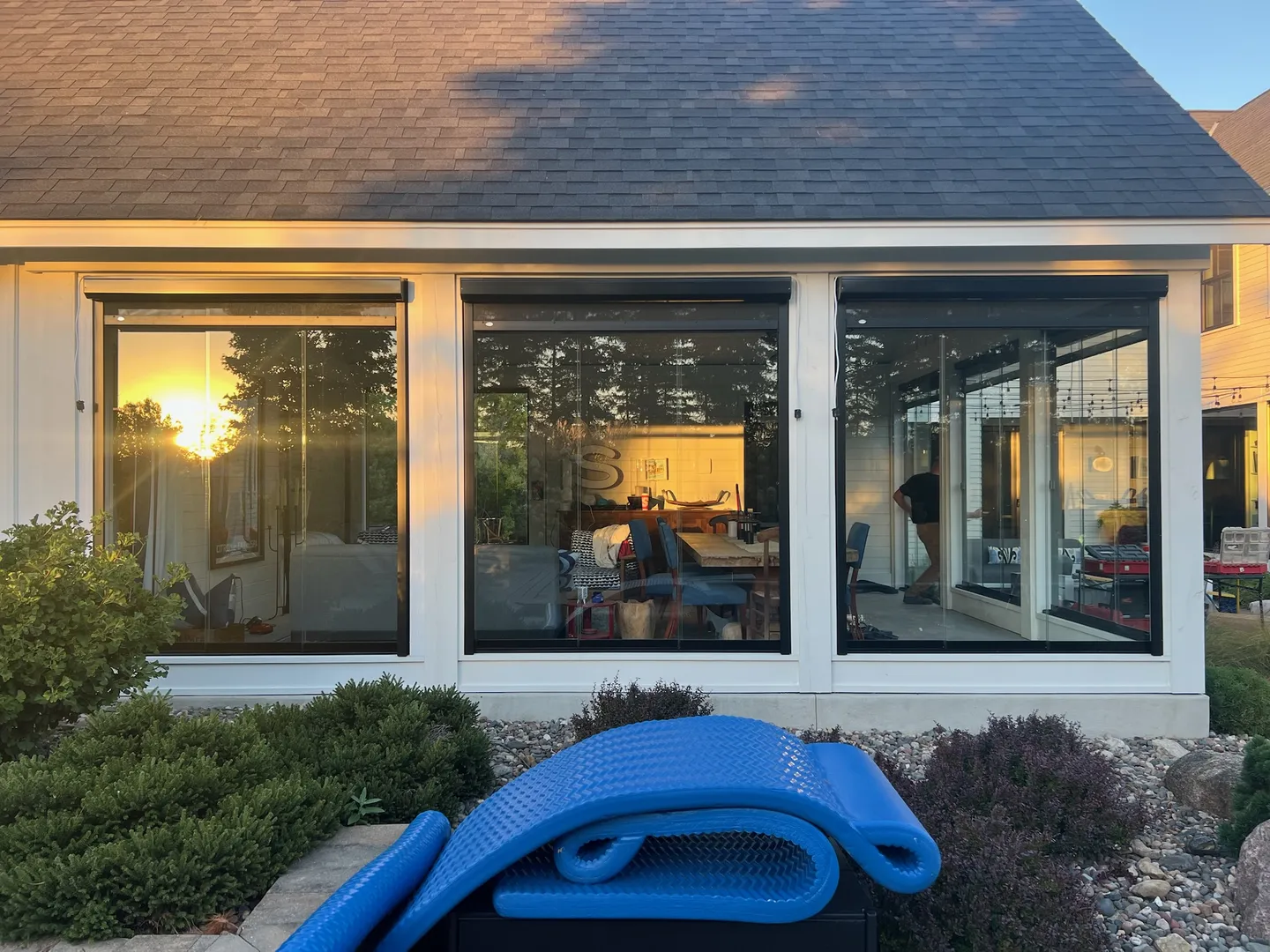 Sunset reflected in the glazed porch of a modern farmhouse
