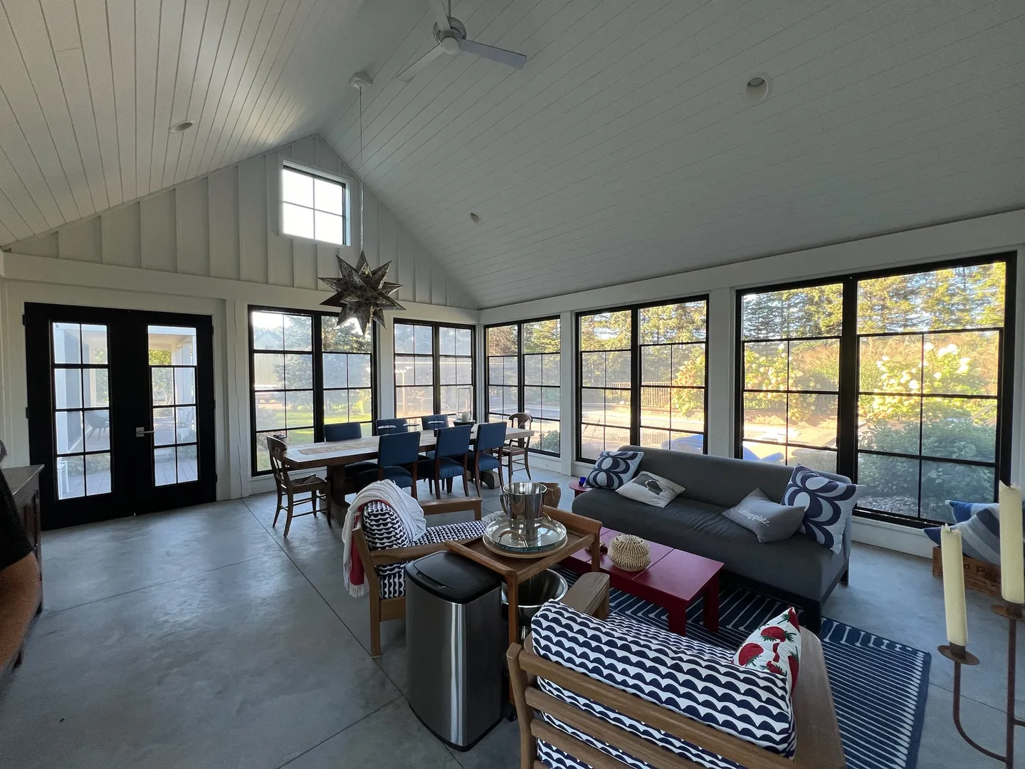 Bright four-season porch interior with vaulted white ceiling and morning light