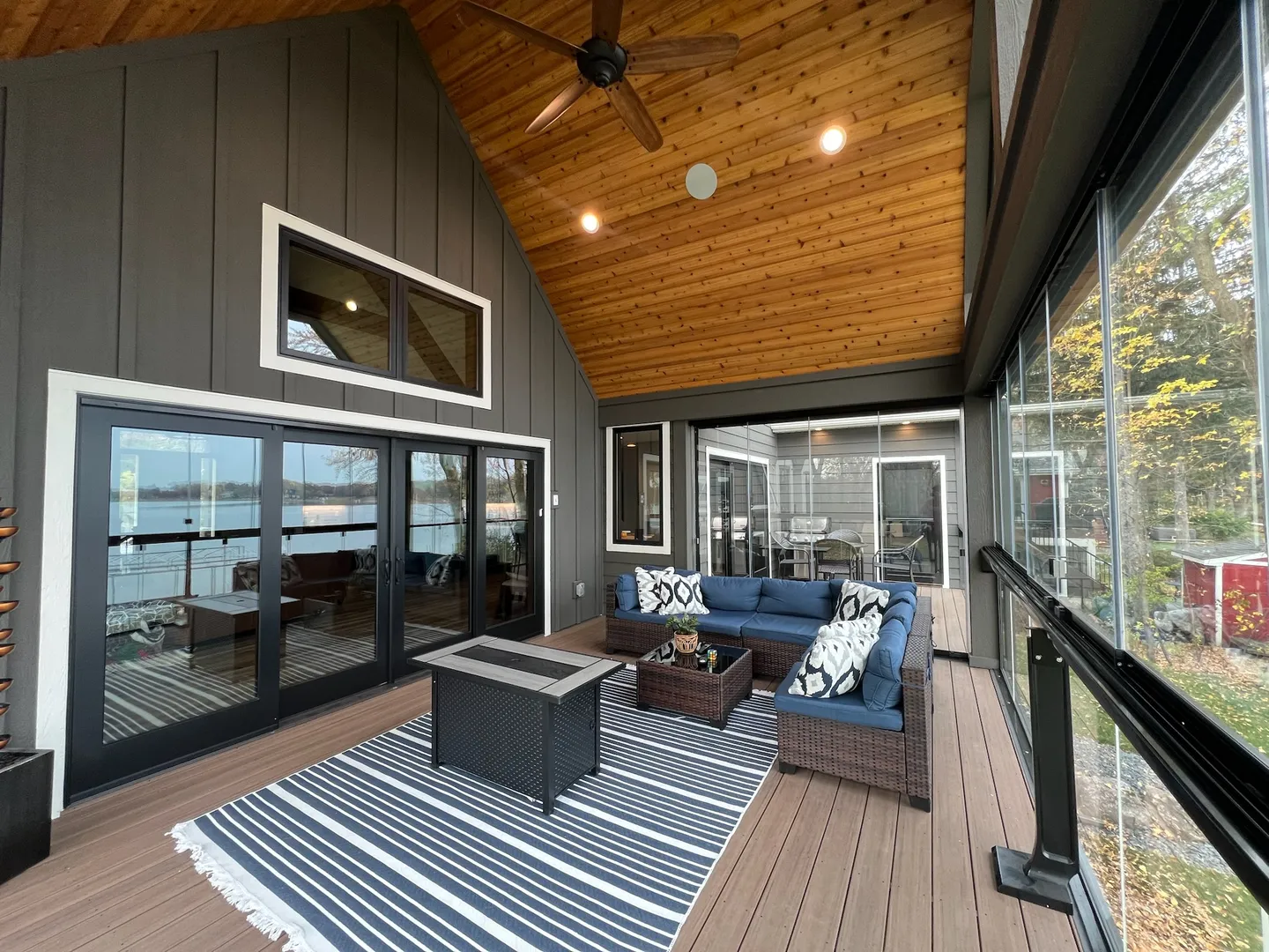 Covered lakeside porch with fire table behind frameless glass