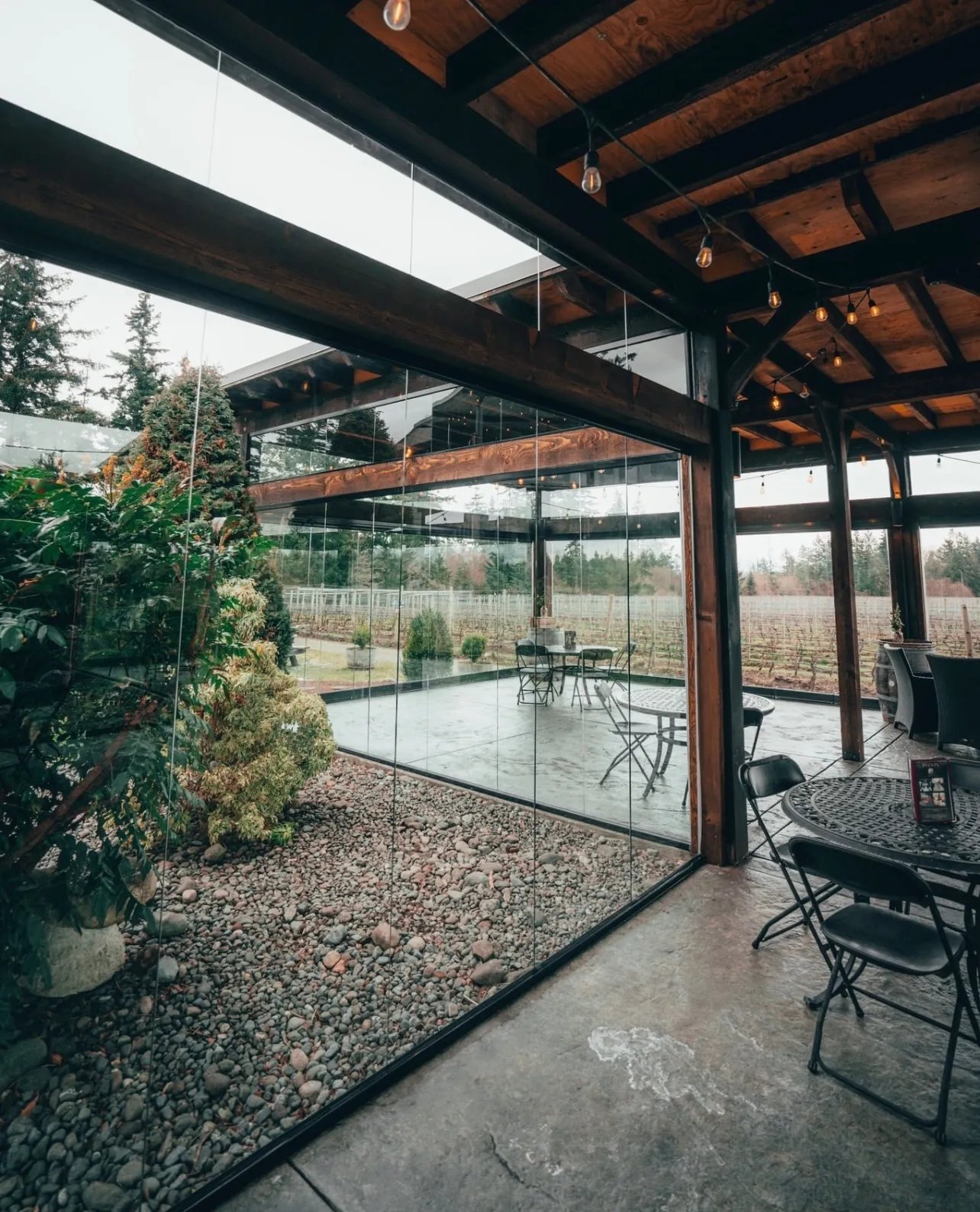 Rain-soaked patio and vineyard seen through frameless glass walls